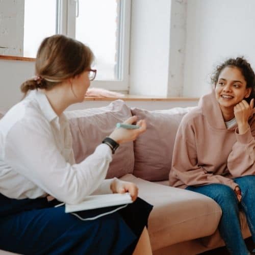 Image of a person sitting on  couch receiving advice from a life coach. Find an online life coach.
