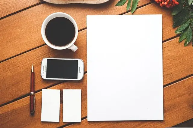 coffee, cellphone, and blank notebook for writing a personal mission statement template on.