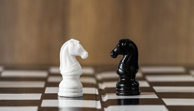 strategic thinking exercises.
Chess board with a black and white knight facing each other.